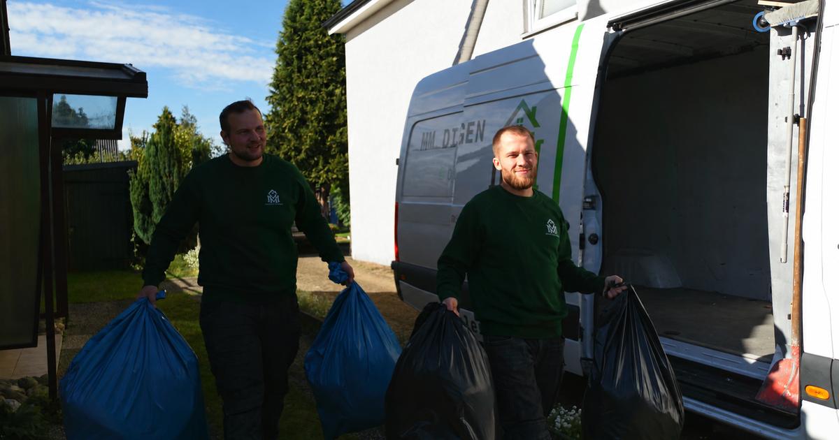 Meik Mroz und Pascal Vagts von MM Dienstleistungen tragen volle Müllsäcke durch einen Garten zu ihrem geöffneten Transporter